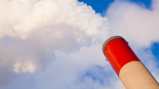 Thick, white smoke rising out of a power plant’s pipe.