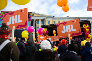 Ammattilitto JHL:n kylttejä ilmassa Stop nyt -mielenosoituksessa. Painava syy.