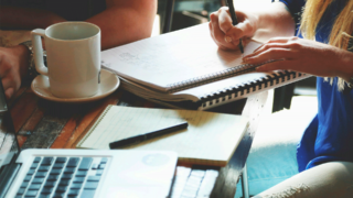 A person is sitting at a desk and making notes.