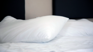 A bed with a white pillow and sheet.